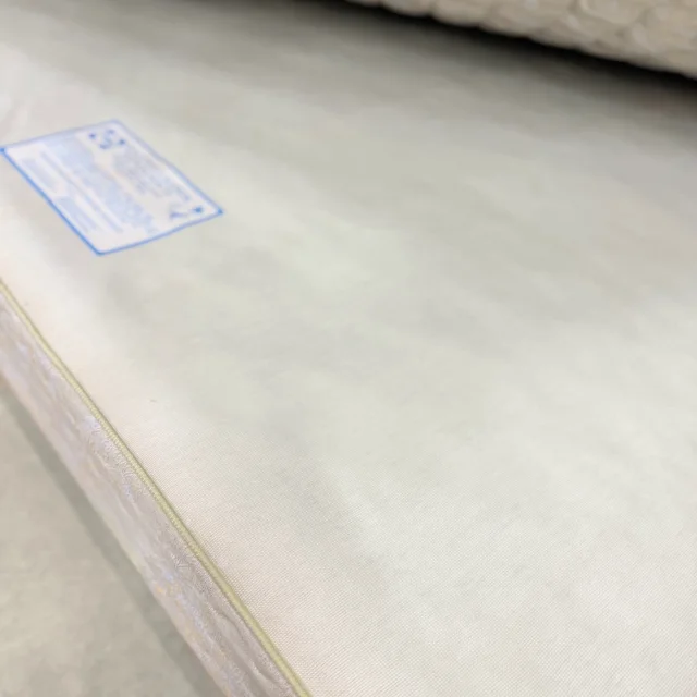 Top of the Sealy base and its piped damask edge, mattress lifted