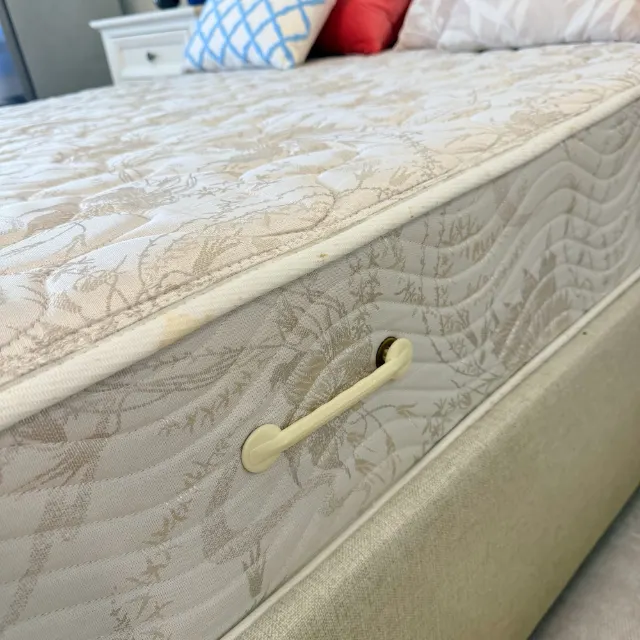 Side panel of the queen mattress with a turning handle and quilted damask cover