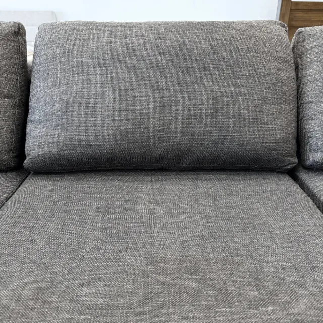 Close-up of a loose back cushion and seat in textured dark grey woven fabric