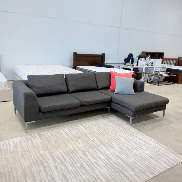 Freedom L shape chaise sofa in dark grey fabric, three-quarter view with the chaise on the right and two scatter cushions
