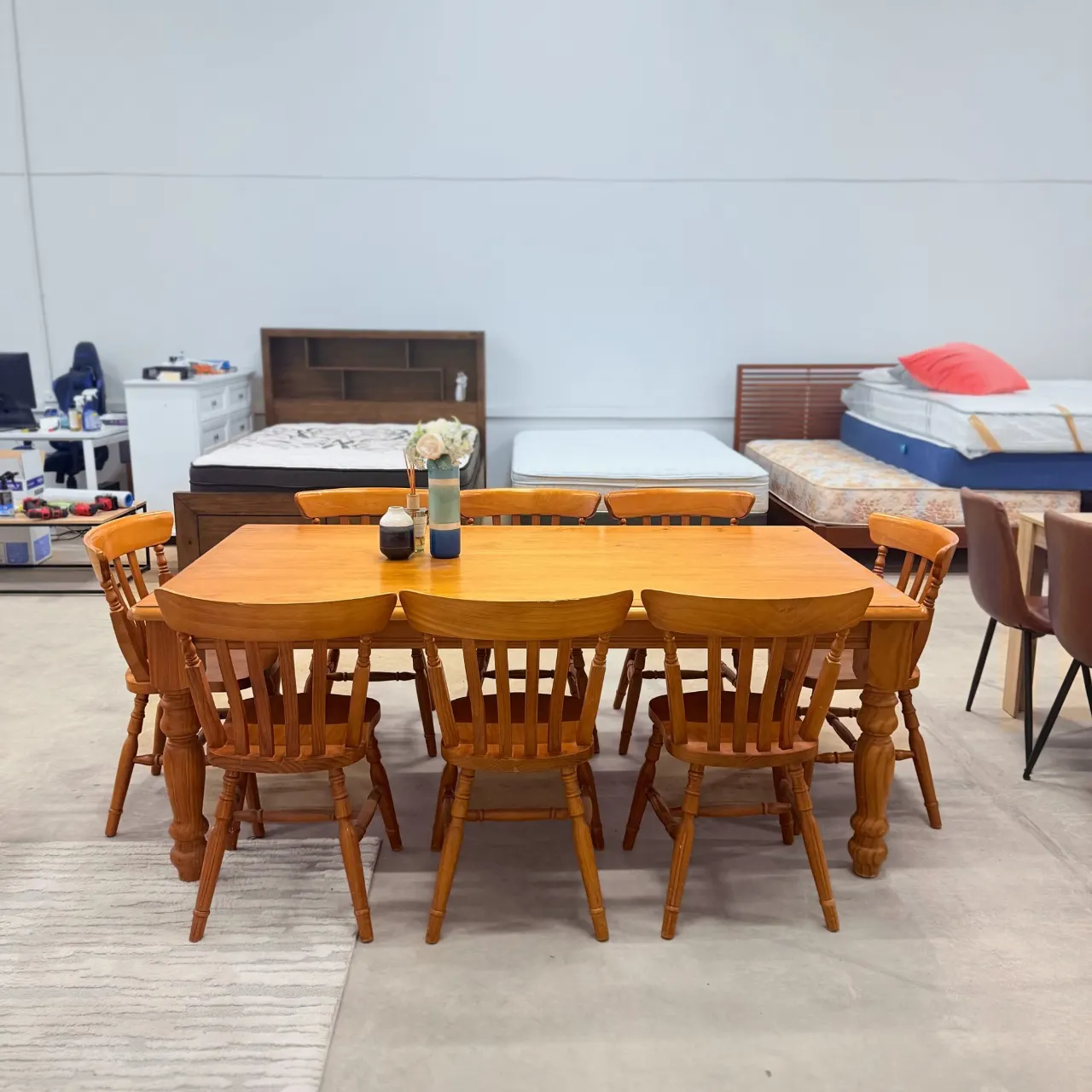 Honey pine dining table with 8 slat-back chairs, front view