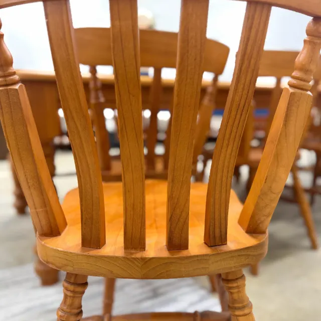 Curved slat back of a honey pine dining chair