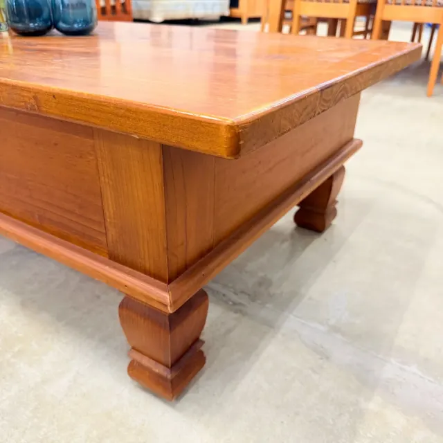 Corner of the pine coffee table: thick rounded top edge, panelled apron and leg