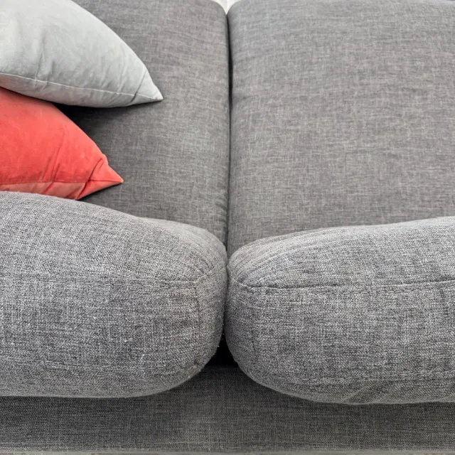 Front edges of the seat cushions close-up: charcoal weave with light pilling