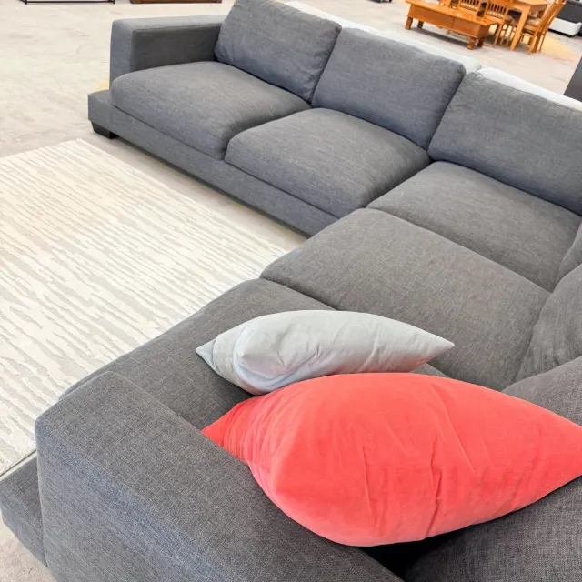Corner lounge from above the end arm: long run of deep seat cushions with coral and grey scatter cushions