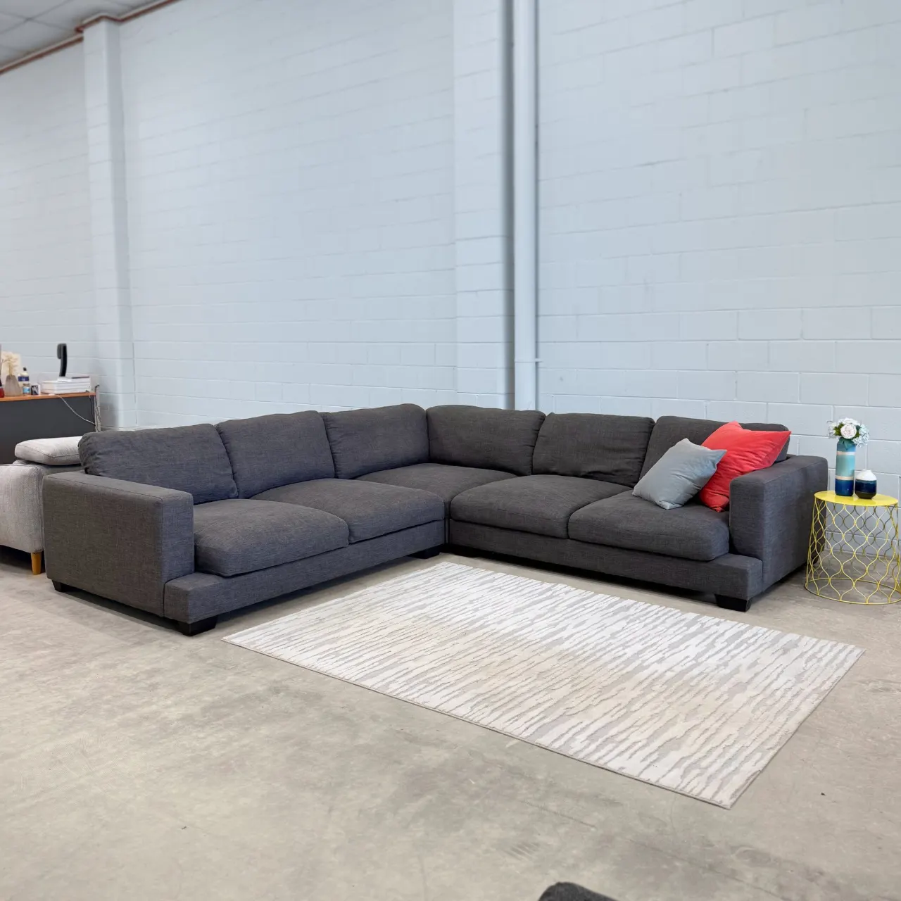 Big charcoal grey fabric corner lounge in the showroom, front view of the whole L shape