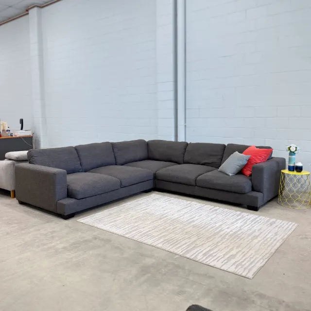 Big charcoal grey fabric corner lounge in the showroom, front view of the whole L shape