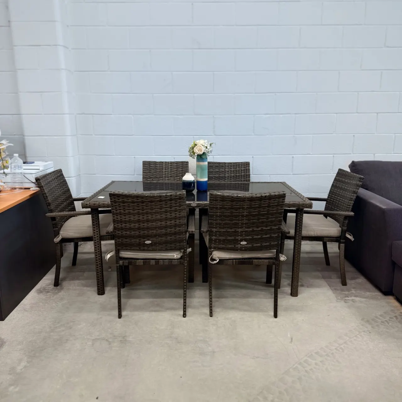 Riva outdoor wicker dining set with a black glass-top table and 6 cushioned armchairs
