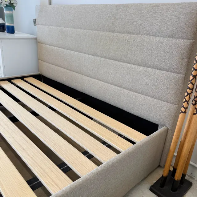 Channel-stitched upholstered headboard above the timber slats