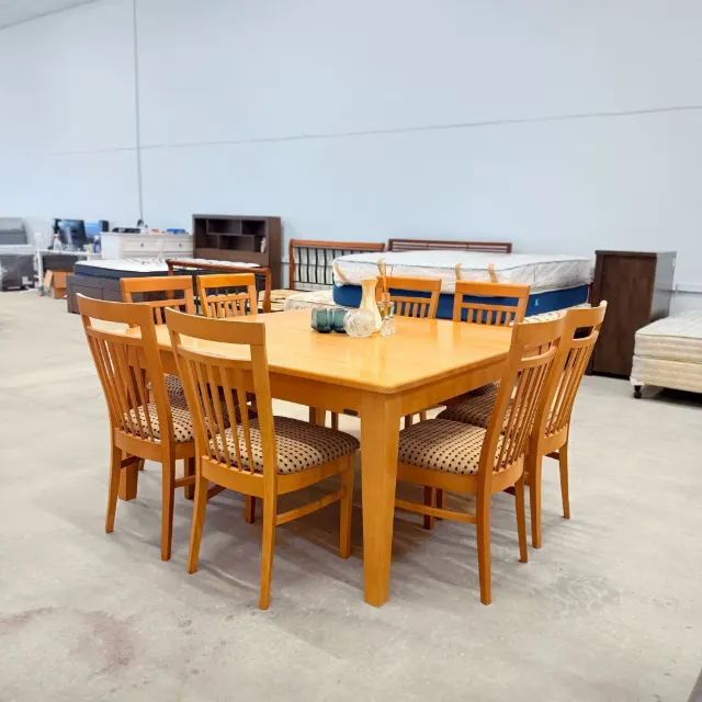 Square timber dining table with 8 slat-back chairs, three-quarter view