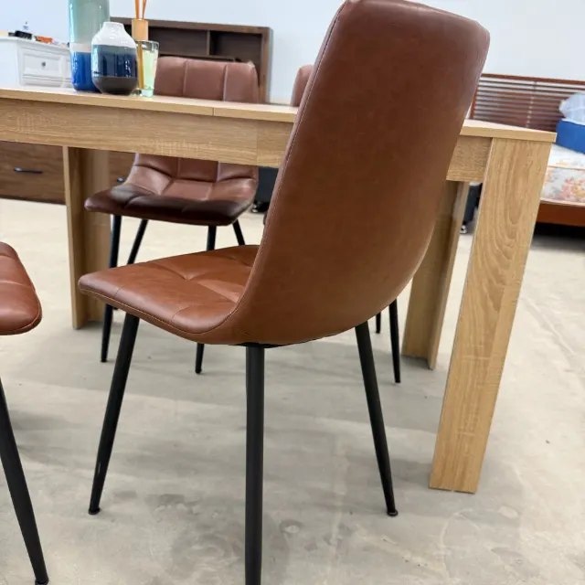 Back of the tan faux leather dining chair on black metal legs