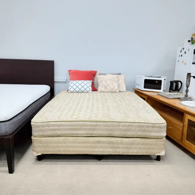 Sealy queen ensemble seen from the foot, matching base and mattress on castors