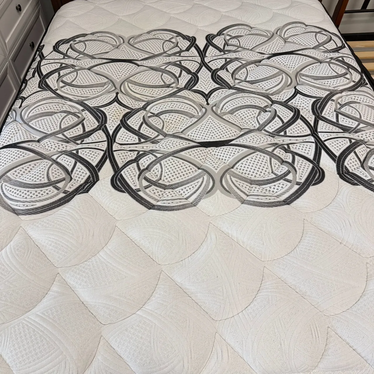 Quilted pillow top with a grey swirl pattern, seen from the foot of the mattress