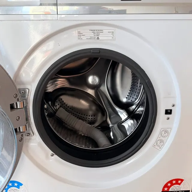 Washer door open showing the stainless steel drum