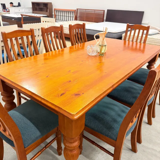 Glossy timber table top with a rounded edge, teal chair seats around it