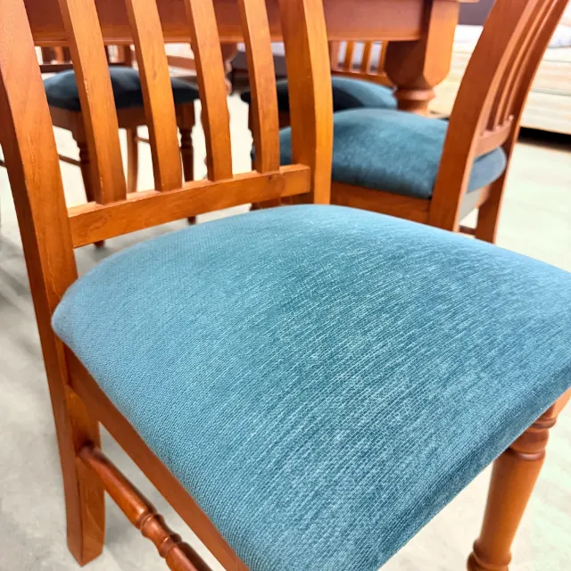 Close-up of the padded teal fabric seat and slatted chair back